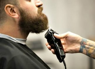 barber using beard trimmer on mans facial hair
