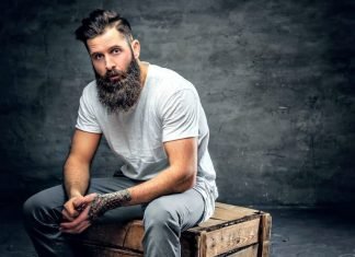 guy with long facial hair sitting on a bench