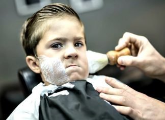 little kid getting a shave at a barber shop