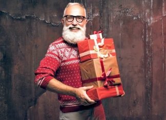 man with a beard in christmas spirits holding a stack of gifts