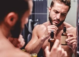 man looking at beard oil ingredient label