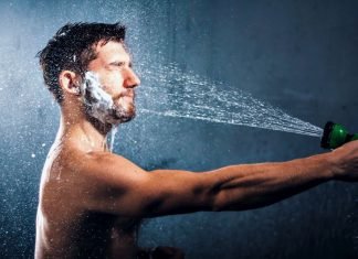 man washing his beard with a garden hose